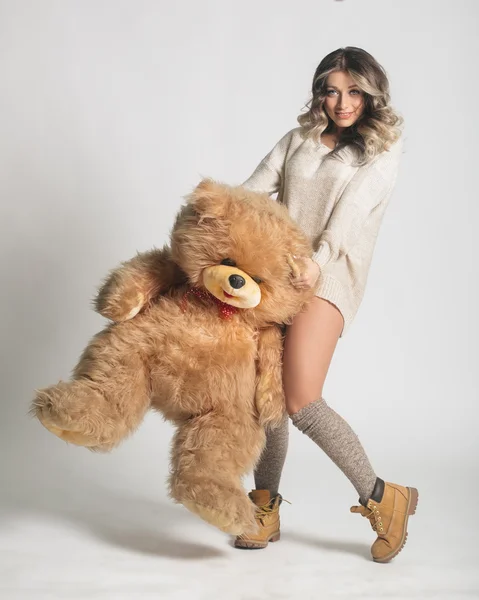 Casual sonriente mujer joven en ropa de invierno sosteniendo grande suave t —  Fotos de Stock