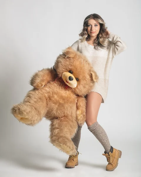 Casual sonriente mujer joven en ropa de invierno sosteniendo grande suave t —  Fotos de Stock