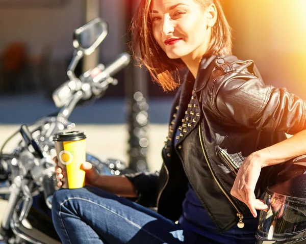 Chica motociclista en una chaqueta de cuero en una motocicleta bebiendo café —  Fotos de Stock