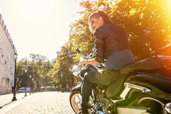 Menina motociclista em uma jaqueta de couro montando uma motocicleta — Fotografia de Stock