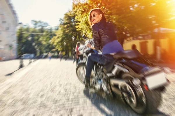 Chica motociclista en una chaqueta de cuero montando una motocicleta — Foto de Stock
