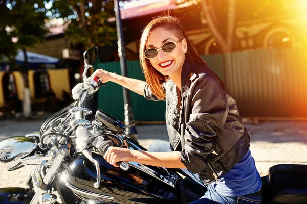 Chica motociclista en una chaqueta de cuero montando una motocicleta — Foto de Stock
