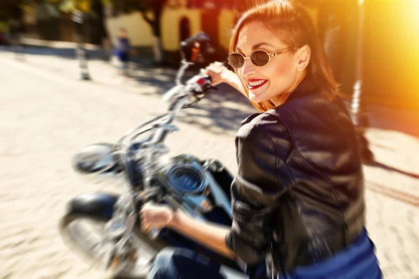 Biker girl in a leather jacket riding a motorcycle — Stock Photo, Image