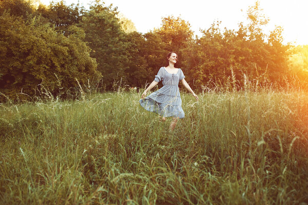 Beauty romantic woman outdoors walking in a field. Light leak effect.