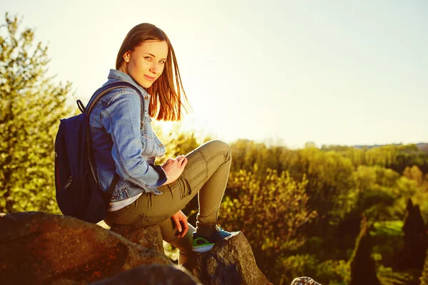 Młoda kobieta z plecaka siedzi na klifie — Zdjęcie stockowe
