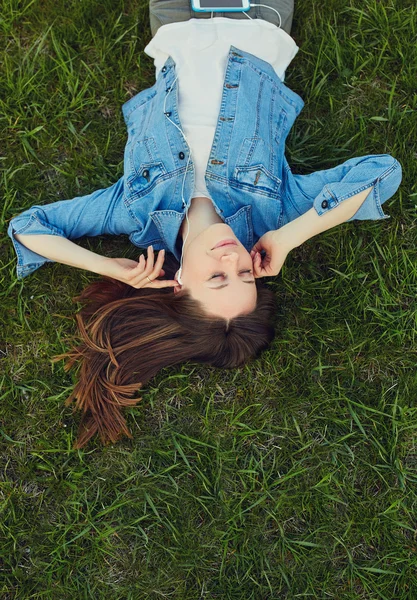 Jonge vrouw luisteren muziek in het park — Stockfoto