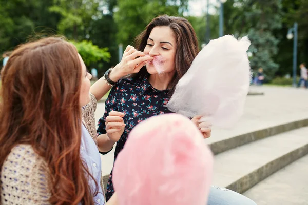 Two sisters eating cotton candy at the park — Stock Photo, Image