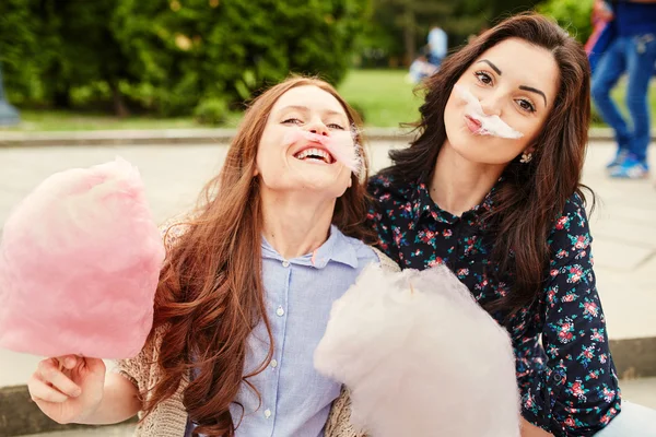 Two sisters eating cotton candy at the park — Stock Photo, Image