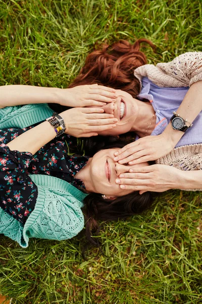Twee vrolijke zusters liggen op het gras — Stockfoto