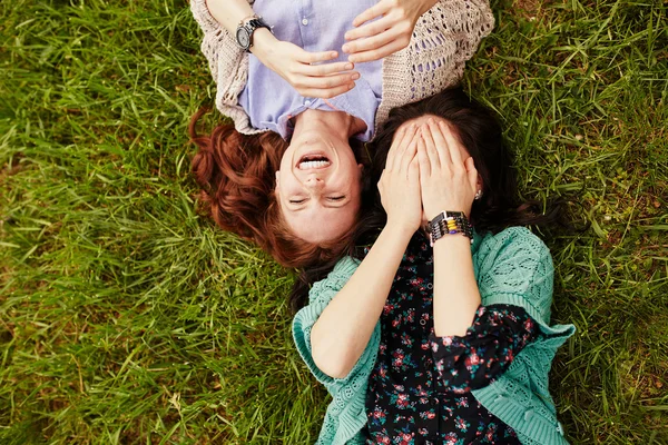 Zwei fröhliche Schwestern liegen im Gras — Stockfoto