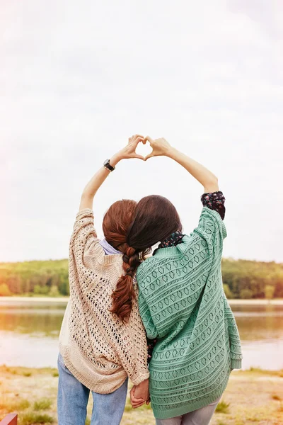 Dos hermanas con pelos entrelazados haciendo el corazón por encima de sus cabezas — Foto de Stock