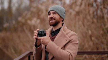 Erkek fotoğrafçı kamerasıyla güzel anları çekerken gülümser..