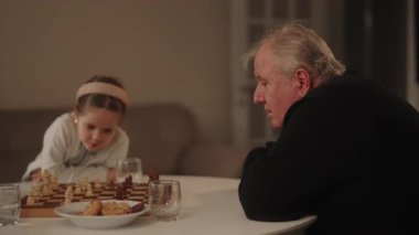 Bilge bir büyükbaba iki küçük torununa satranç oyununda rehberlik eder..