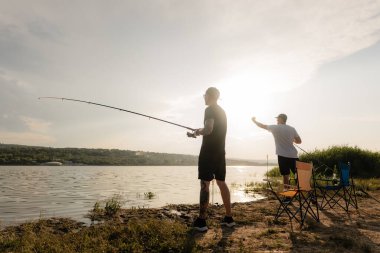Gün batımında göl kıyısında balık tutan iki adam dinlendirici bir hobi ve sessiz bir arkadaşlığın tadını çıkarıyorlar..