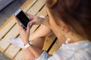 Akıllı telefon kullanarak bir palet üzerinde oturan sevimli kız