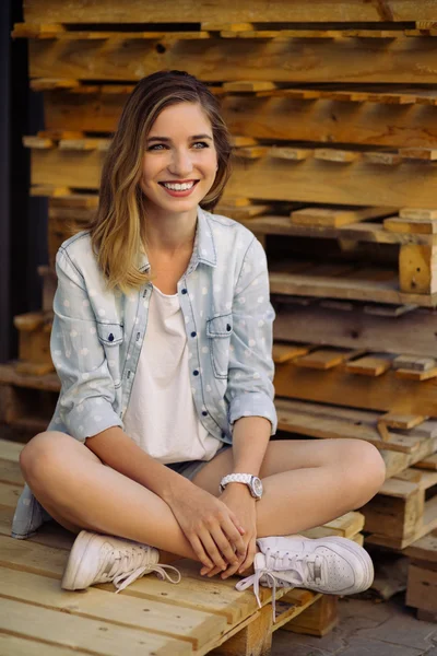 Charmante meisje, zittend op een pallet — Stockfoto