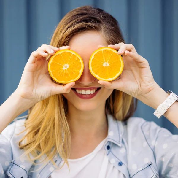 Sorrindo mulher segurando duas laranja nas mãos — Fotografia de Stock