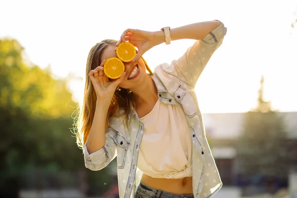 Smiling woman holding two orange in hands — Stock Photo, Image