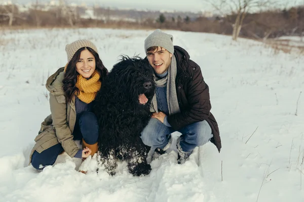 Pareja joven paseando con un perro en un día de invierno — Foto de Stock