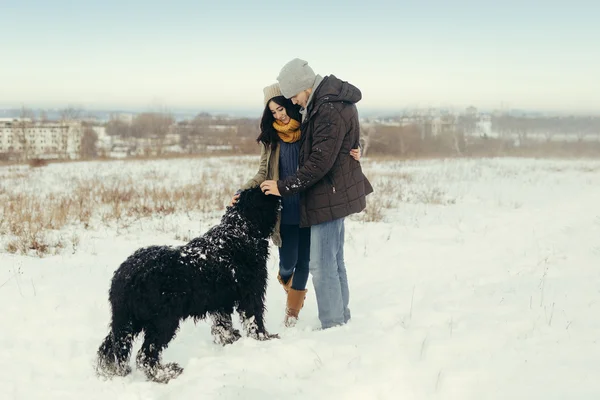 Ungt par promenader med en hund i en vinterdag — Stockfoto