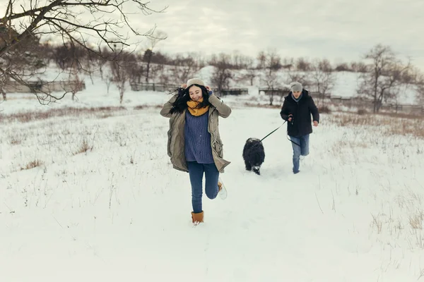 Pareja joven paseando con un perro en un día de invierno — Foto de Stock