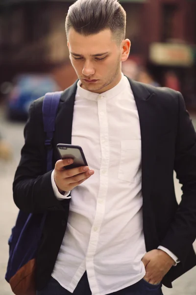Young man with backpack holding a phone — Stock Photo, Image