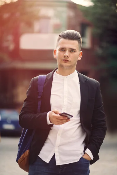 Young man with backpack holding a phone — Stock Photo, Image