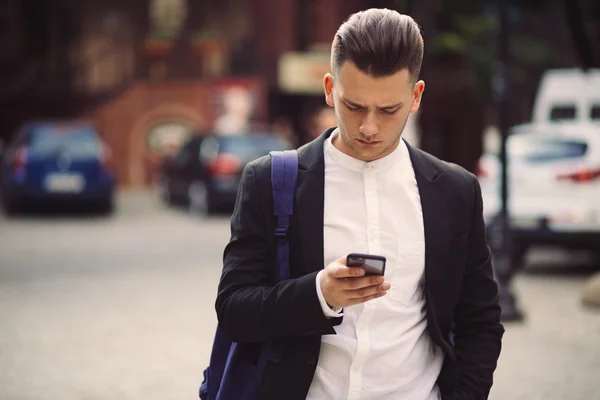 Young man with backpack holding a phone — Stock Photo, Image