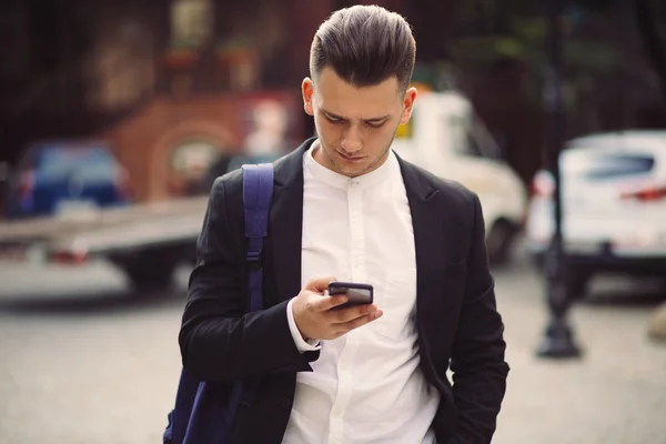 Young man with backpack holding a phone — Stock Photo, Image