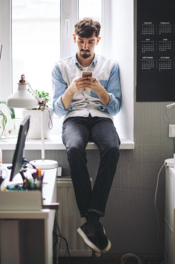 Cep telefonu kullaranarak ofisinde çalışan yakışıklı işadamı