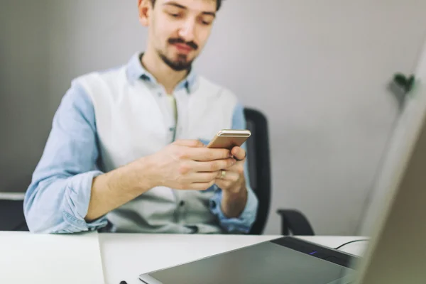 Schöner Geschäftsmann, der im Büro mit dem Handy arbeitet — Stockfoto