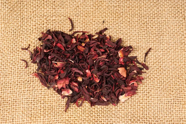 Hibiscus tea macro dry flower on sackcloth background — Stock Photo, Image