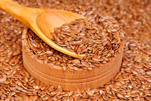 I semi di lino in una ciotola di legno e cucchiaio da vicino — Foto Stock