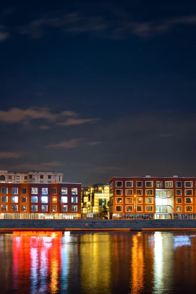 Night view from another side of the river from embankment to business buildings and reflection on water from window light — Stock Photo, Image