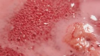 Kaynama sürecinde ahududu reçeli. Ahududu şurubu. Kabarcık ve ahududu köpüklü pembe arka plan. Kış için böğürtlen toplama prosedürü. Şekerli ahududu pişirmek. Arka plan baloncukları göze hoş gelir..