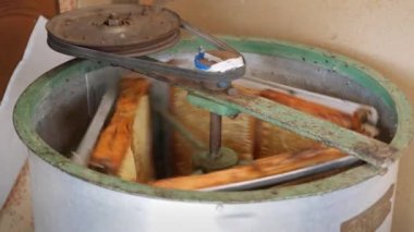 Bal peteğinden balın çıkarılması. Bal sökücü çerçevelerle dönüyor bal petekleri, bal pompalama. Bal peteğinden bal alıyorum, yakın plan. Güç odaklı bir operasyon. Belt sürücüsü. Çıkarıcı. Bal kazanıyorum. ProRes