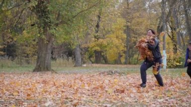 Açık hava oyunları. Sonbahar manzarası. Sonbahar. Çocuklar devrilmiş ağaç yapraklarıyla oynarlar. Çocuk süzülen sonbahar sarı yaprakları arasında koşar..