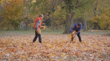 Erkekler birbirlerine düşen sonbahar yapraklarını fırlatırlar..