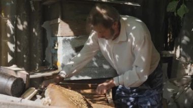 Arı kovanında sakallı bir arı yetiştiricisi. Arı yetiştiricisi bal topluyor. Arıcılık konsepti.