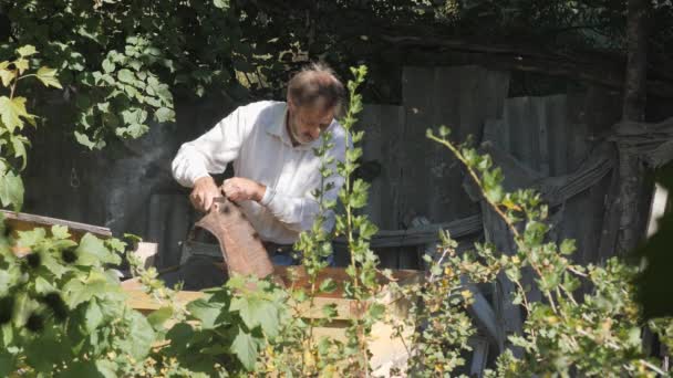 Opening of a bee hive. Removing the canvas from the honey frames. A man with a beard, a beekeeper, in the apiary. Beekeeper working collect honey. Beekeeping concept. — Stockvideo
