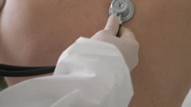 Hastanın muayenesi. Bir fonendoskopla akciğerleri dinlemek..