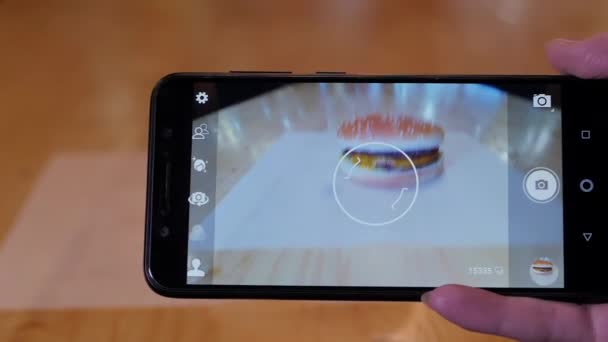 Ženský ruce fotí na mobilním telefonu hamburger s hovězím koláčem s roztaveným sýrem. — Stock video
