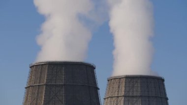 Kış gökyüzü. Termal elektrik su ikmal istasyonunun soğutma kulesinden çıkan buhar. Bacadan duman çıkıyor..