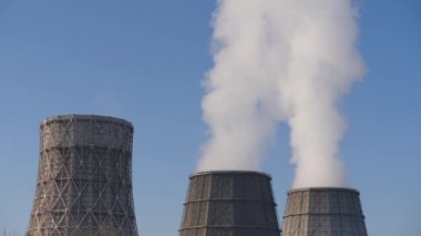 Kış gökyüzü. Termal elektrik su ikmal istasyonunun soğutma kulesinden çıkan buhar. Bacadan duman çıkıyor..