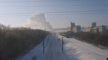 Benzini olan dizel lokomotif tren rayları boyunca ilerliyor. Bacadan duman çıkıyor..