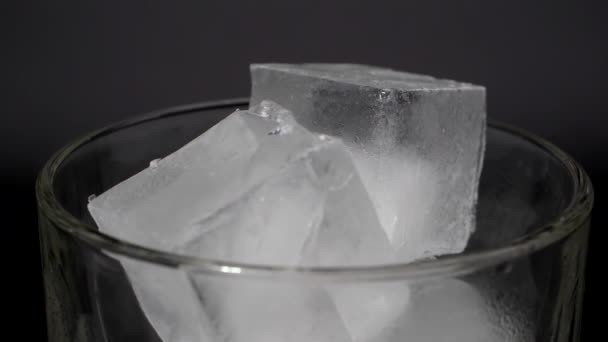 Eiswürfel in einem Glas auf schwarzem Hintergrund. — Stockvideo