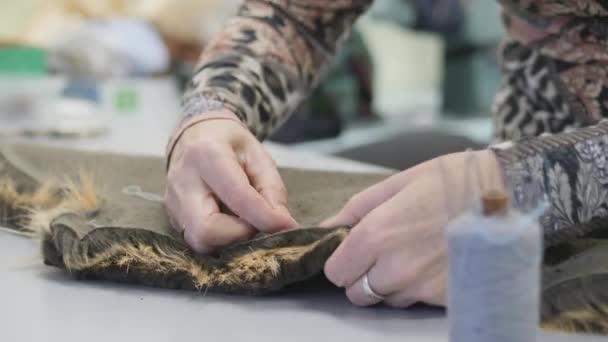 재봉 작업장. 두 개의 가짜털을 손으로 꿰매고 있다. 바늘 과 실로 바느질하는 일. — 비디오