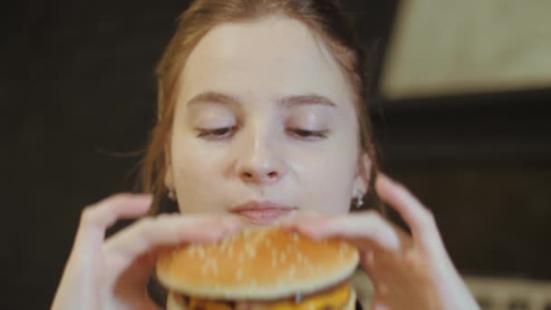 Mladá žena kousne zábavu na burger. — Stock video