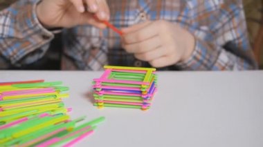 Çocuk renkli çubuklardan bir piramit inşa ediyor. Tablo oyunları.