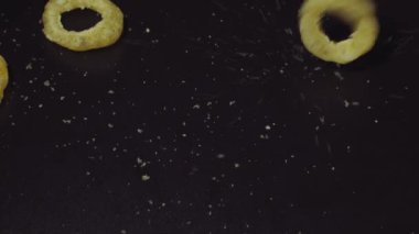 Siyah arka planda dönen mısır halkaları. Soğan halkaları.